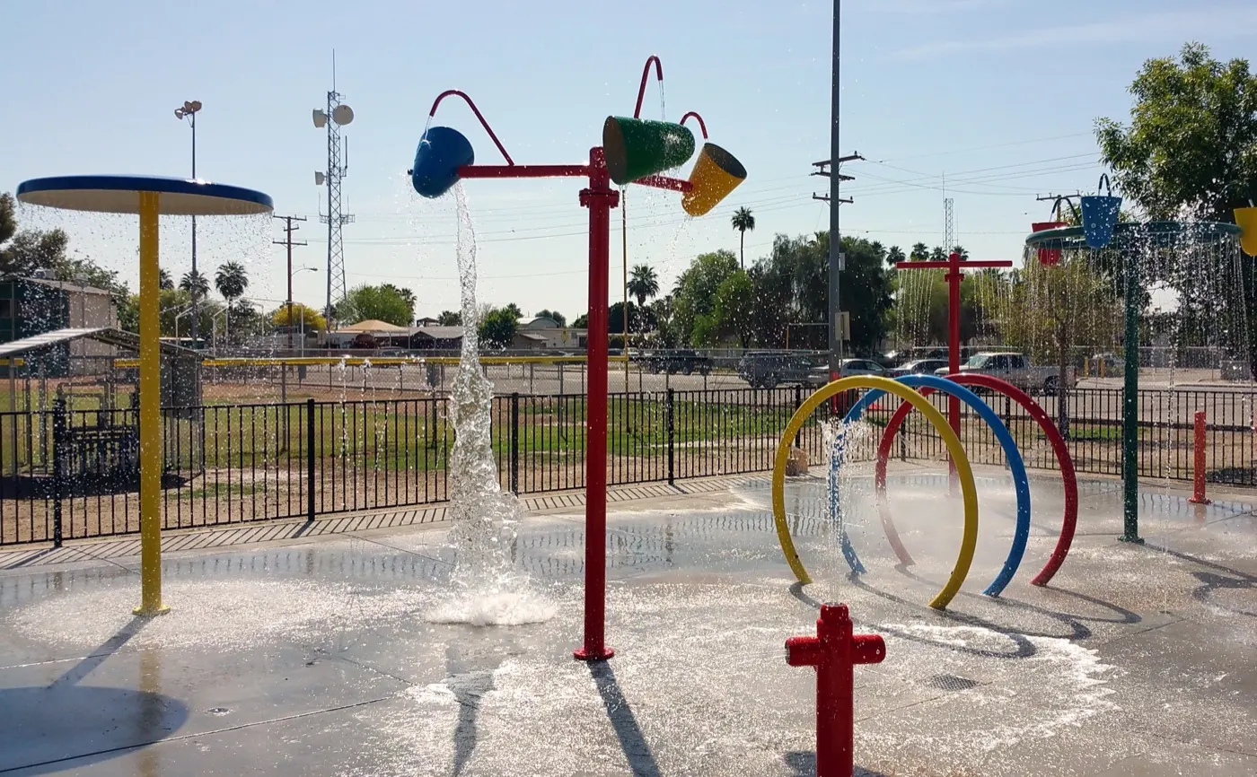 Fenced commercial splash pad with buckets, loops and umbrellas