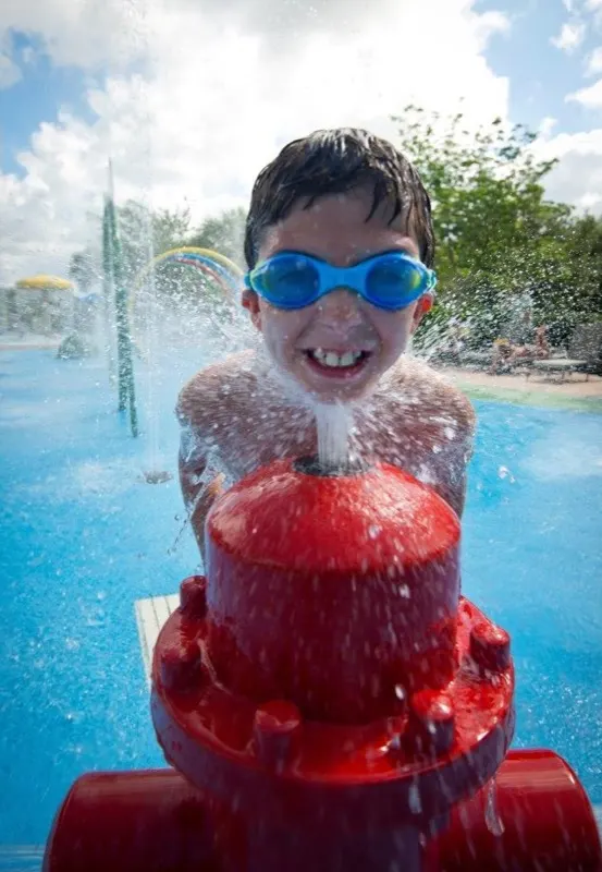 Child laughing as a fire hydrant splash pad feature sprays water