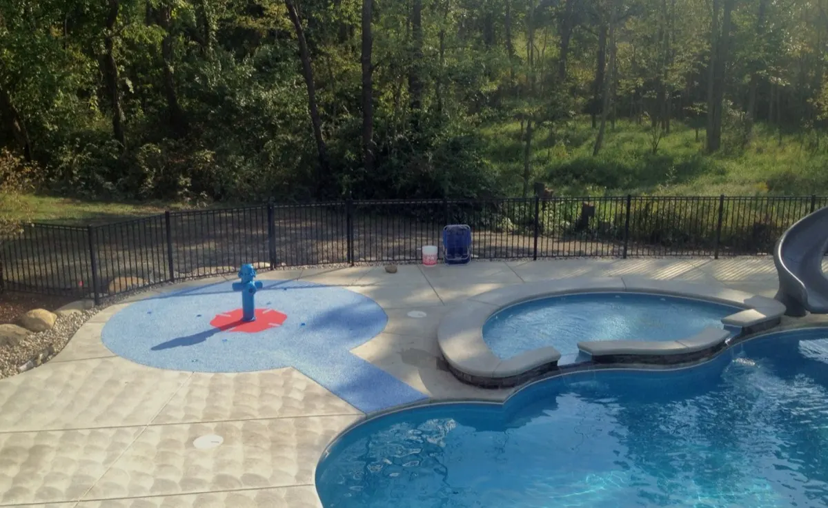 Backyard splash pad with a fire hydrant sprayer built beside a pool and spa